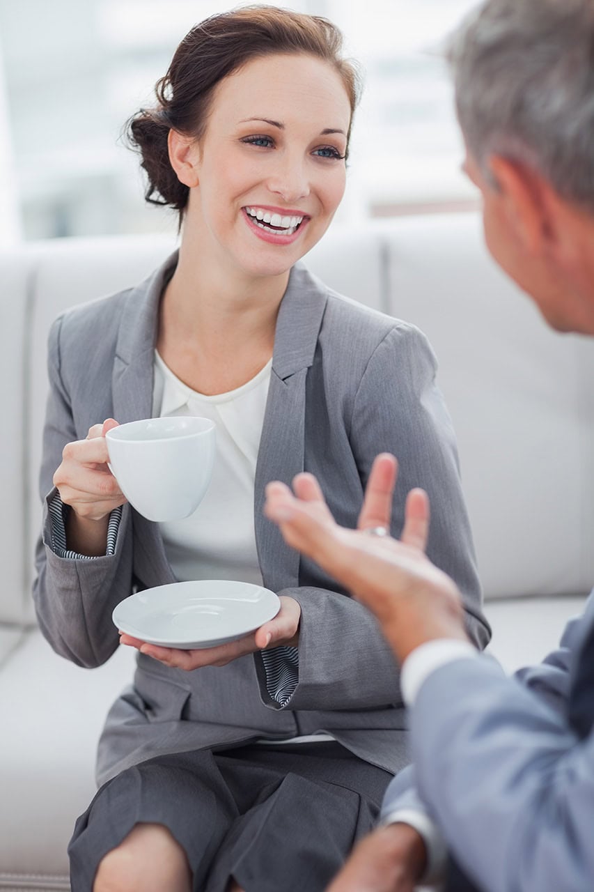 Einzelberatung 1 Kommunikation im Beruf, professioneller Austausch, Geschäftsmeeting, Frau mit Tasse im Gespräch, Business-Umfeld, freundliche Unterhaltung, Geschäftliche Kommunikation, Networking, Büro, professionelles Teamwork.
